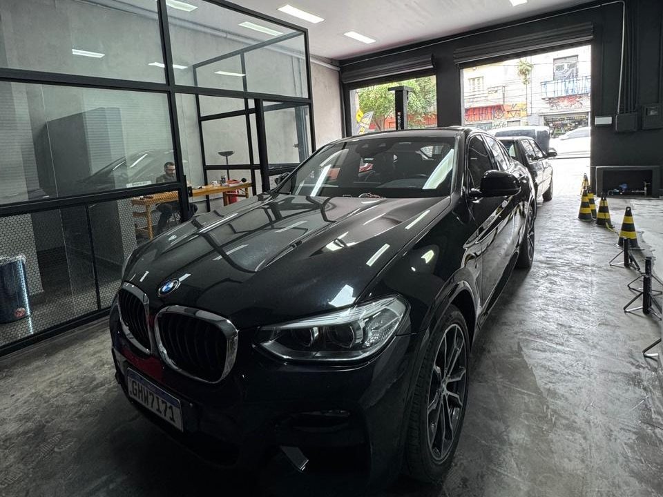 Carro preto no salão do Clube Drive, com o box de vidro ao fundo